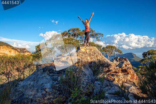 Image of Standing at the top of a rocky cliff arms outstretched achieveme