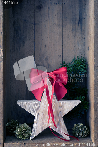 Image of Christmas decoration red ribbon on a star in a wooden box backgr