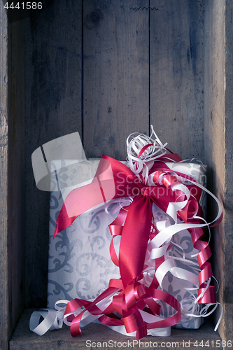 Image of Christmas present with a red ribbon in a wooden box background