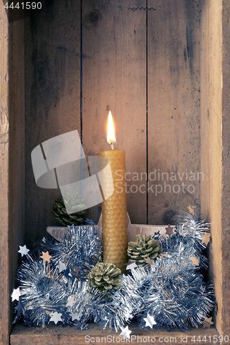 Image of Christmas decoration orange bee wax candle in a wooden box backg