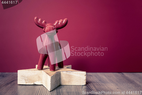 Image of Christmas decoration wooden star with red deer background