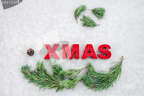 Image of Pine branches and the word Xmas on gray background
