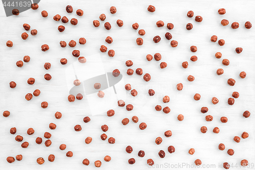 Image of Peeled hazelnuts on white wooden background