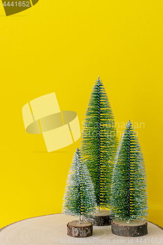 Image of Christmas decoration three fir trees in front of a yellow backgr
