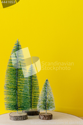 Image of Christmas decoration three fir trees in front of a yellow backgr