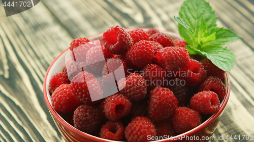 Image of Bowl of raspberry on wooden desk 