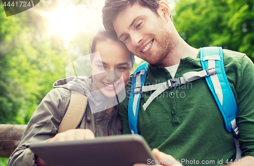 Image of happy couple with backpacks and tablet pc outdoors