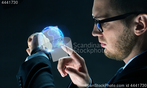 Image of businessman with smart watch and earth hologram