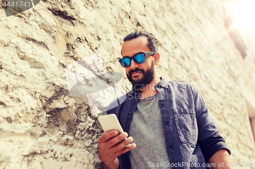 Image of man texting message on smartphone at stone wall