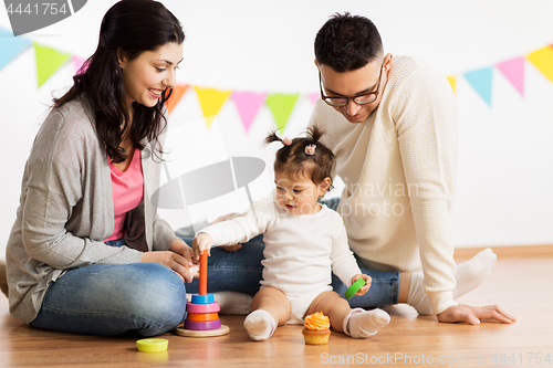 Image of baby girl with parents playing with pyramid toy