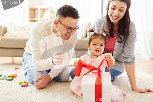 Image of baby girl with birthday gift and parents at home