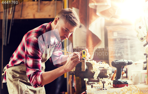 Image of carpenter with ruler measuring plank at workshop