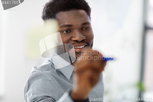 Image of businessman writing on glass board at office