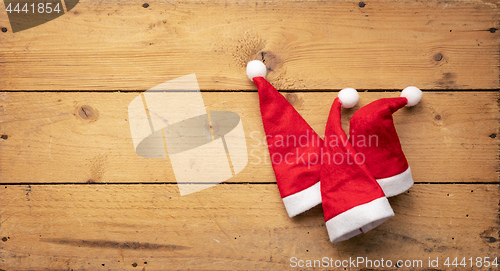 Image of three red Santa Claus hats with wooden background