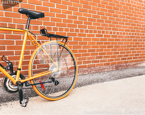 Image of Orange bicycle near red brick wall with copy space