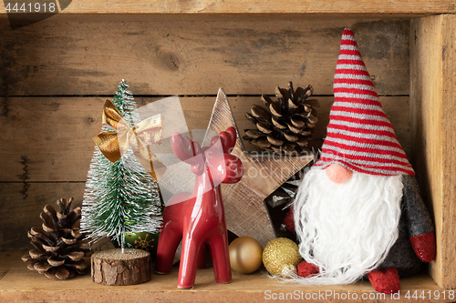 Image of Christmas decoration deer figure and gnome in a wooden box backg