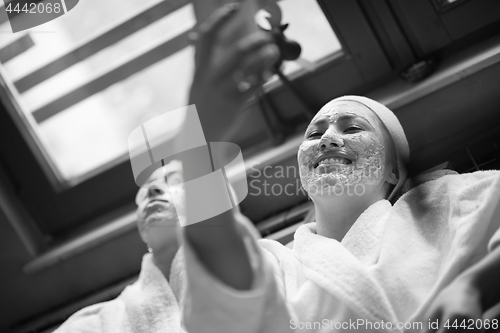 Image of women is getting facial clay mask at spa