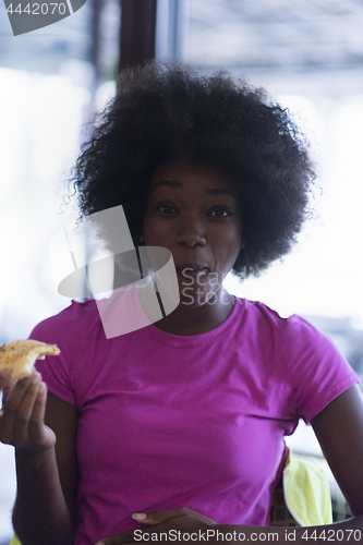 Image of woman with afro hairstyle eating tasty pizza slice