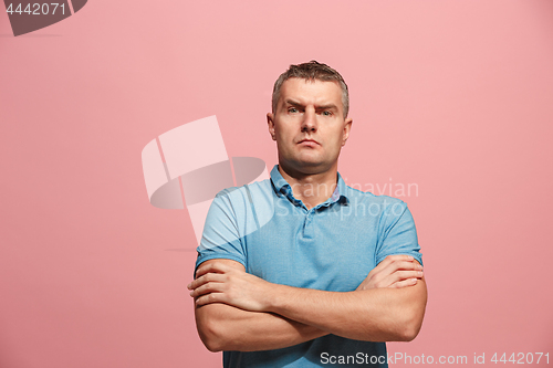 Image of The serious businessman standing and looking at camera against pink background.