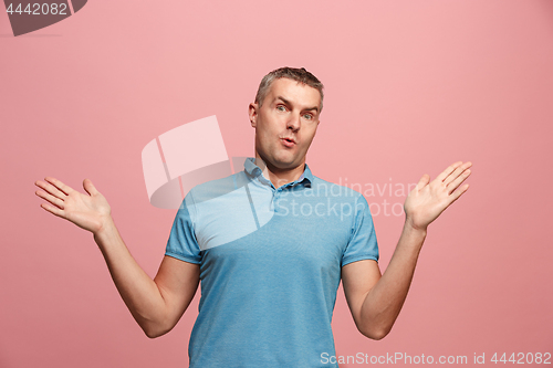 Image of The young attractive man looking suprised isolated on pink
