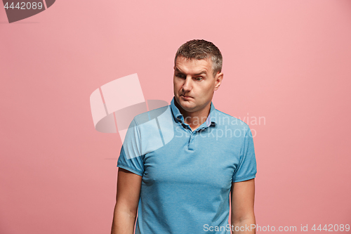 Image of Suspiciont. Doubtful pensive man with thoughtful expression making choice against pink background