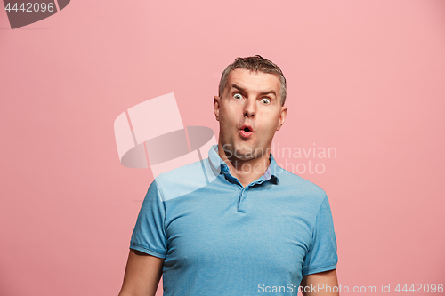 Image of The young attractive man looking suprised isolated on pink