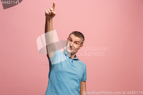 Image of The young attractive man looking suprised isolated on pink