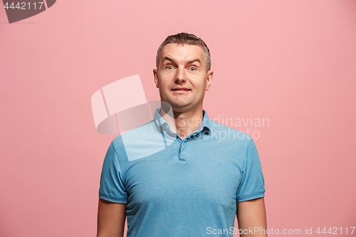 Image of The young attractive man looking suprised isolated on pink