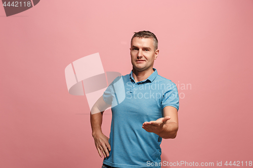 Image of The young attractive man looking suprised isolated on pink