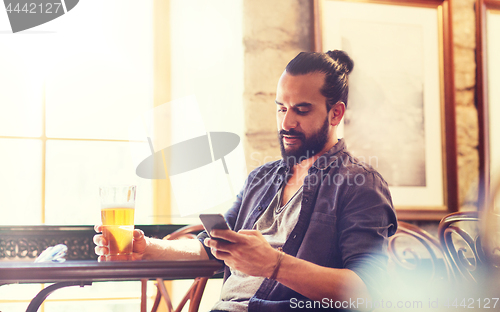 Image of man with smartphone drinking beer at bar or pub