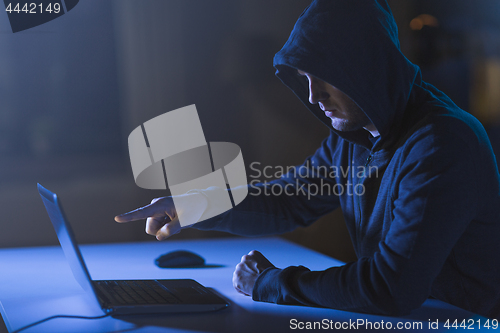 Image of hacker pointing at laptop computer in dark room