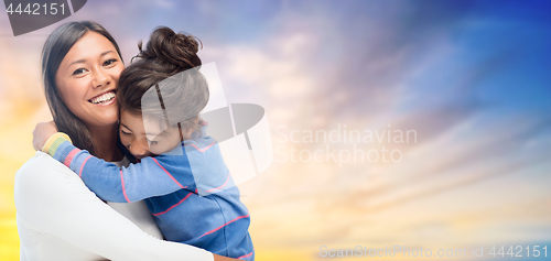 Image of happy mother and daughter hugging over evening sky