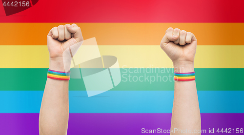 Image of hands with gay pride rainbow wristbands shows fist