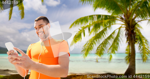 Image of man with smartphone and earphones over beach