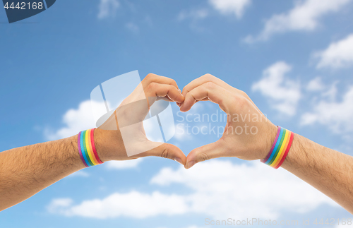 Image of male hands with gay pride wristbands showing heart