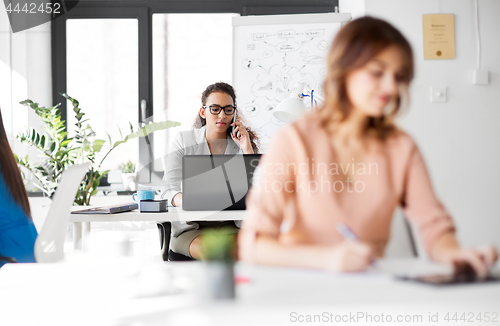 Image of businesswoman calling on smartphone at office