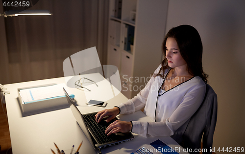 Image of businesswoman with laptop at night office