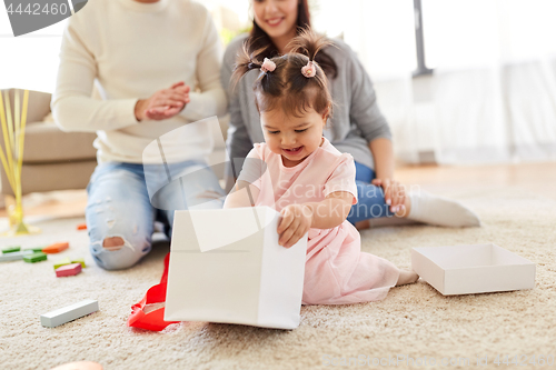 Image of baby girl with birthday gift and parents at home