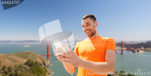 Image of man with smartphone and earphones over golden gate