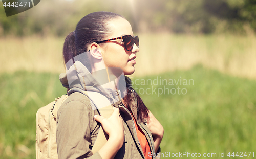 Image of happy young woman with backpack hiking outdoors