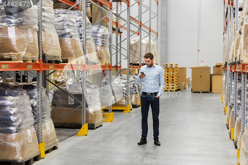 Image of businessman with smartphone at warehouse