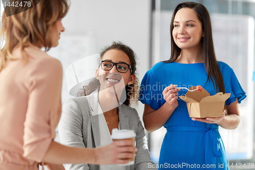 Image of happy businesswomen eating take out food at office