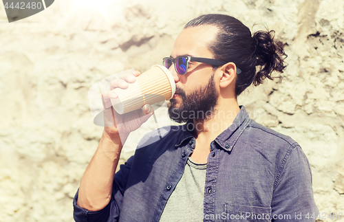 Image of man drinking coffee from paper cup on street