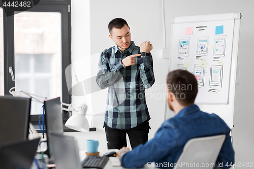 Image of man showing smart watch to creative team at office