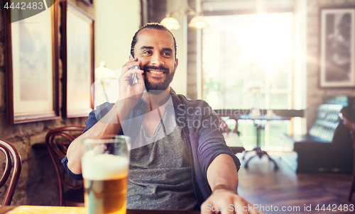 Image of man with smartphone and beer calling at bar or pub