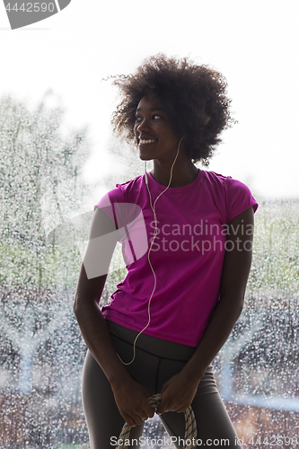 Image of portrait of young afro american woman in gym while listening mus