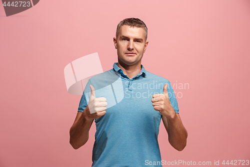 Image of The happy businessman standing and smiling against pink background.