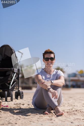 Image of Young mother with sunglasses relaxing on beach