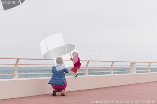 Image of mother and cute little girl on the promenade by the sea