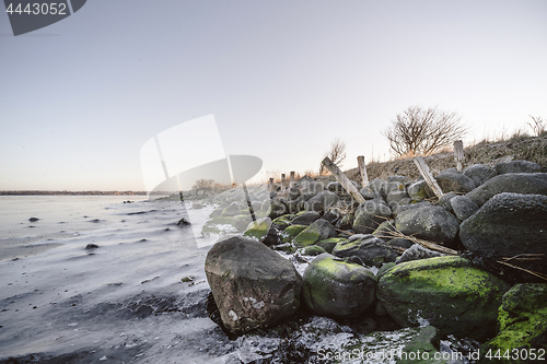 Image of Rocks covered with green moss by a frozen lake